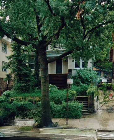 a front view of a house with a tree