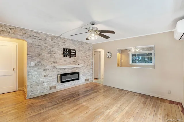 a view of an empty room with a fireplace and wooden floor