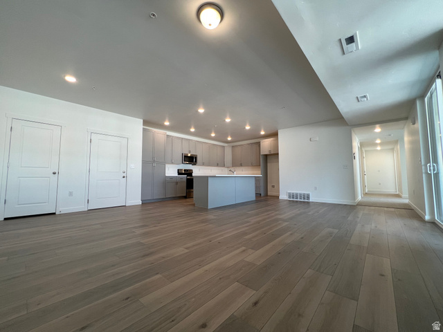 717 West W Coho Lane South, Unit 2F302 Midvale, UT 84047 - Photo 5 of 22 Expansive open-concept living area featuring wood-finish flooring, a modern kitchen with gray cabinetry, a central island, recessed lighting, and a sliding glass door