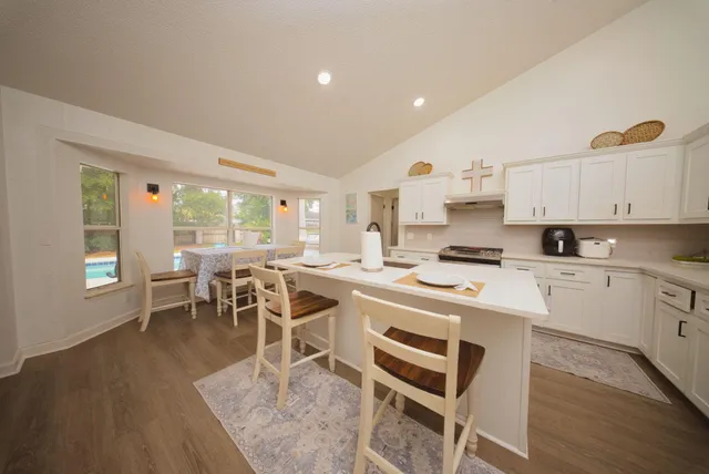 a kitchen with a dining table chairs and white appliances