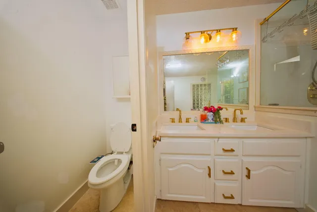 a bathroom with a granite countertop toilet sink and mirror