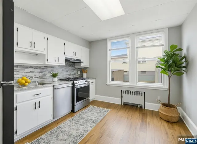 a kitchen with stainless steel appliances granite countertop a stove a sink and a white cabinets