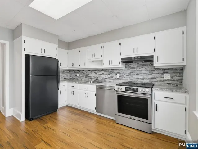 a kitchen with granite countertop white cabinets and stainless steel appliances