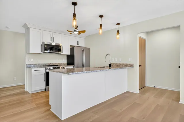 a kitchen with kitchen island white cabinets and stainless steel appliances