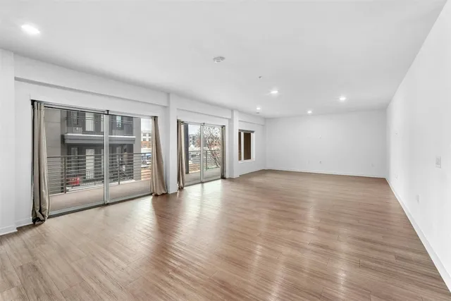 a view of an empty room with glass door and windows