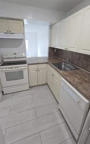 a kitchen with granite countertop white cabinets and white appliances