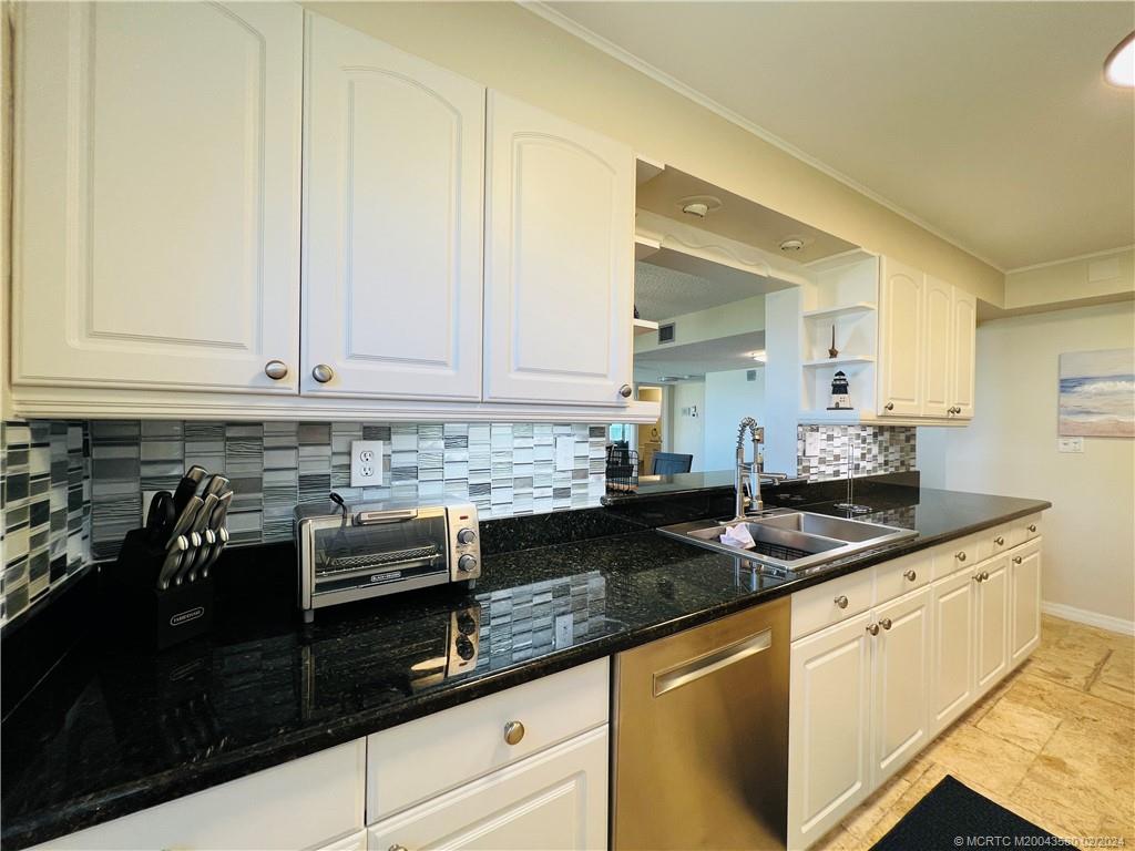 Undisclosed Address Jensen Beach, FL 34957 - Photo 13 of 86 a kitchen with granite countertop white cabinets and black appliances