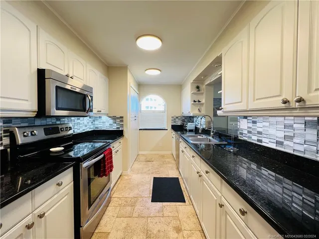 a kitchen with granite countertop white cabinets and black appliances