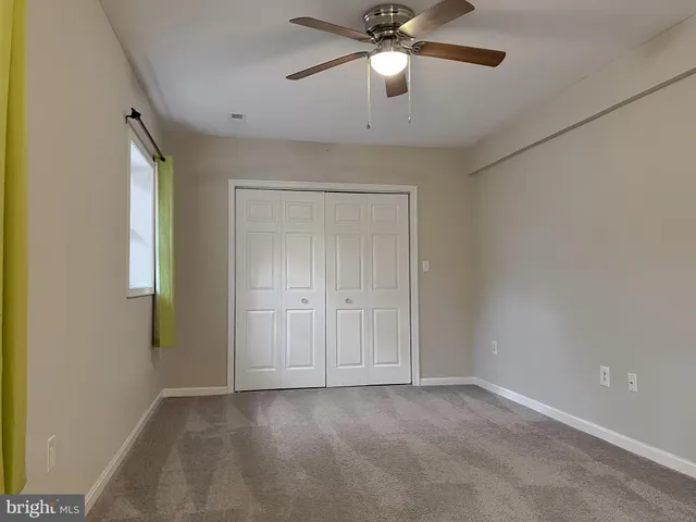 an empty room with closet and a chandelier fan