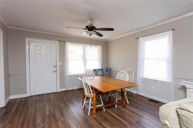 a dining room with wooden floor a chandelier a glass table and chairs