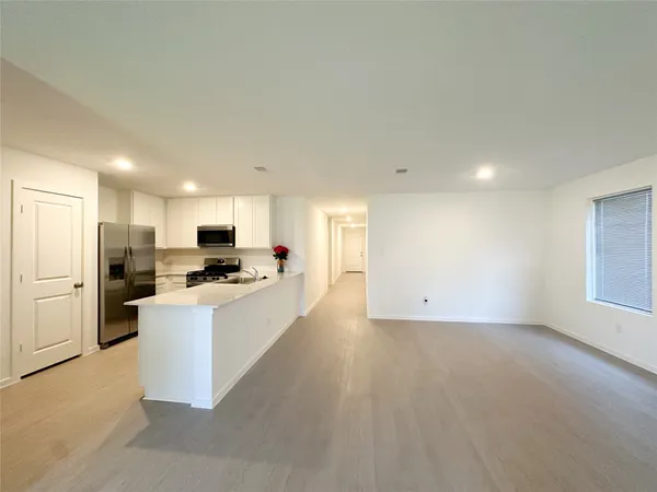 a large white kitchen with a refrigerator a stove top oven a sink and white cabinets