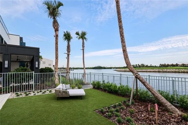 a view of a patio with dining table and chairs with plants and palm trees