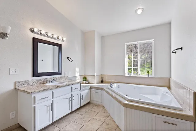 a spacious bathroom with a granite countertop tub sink and mirror