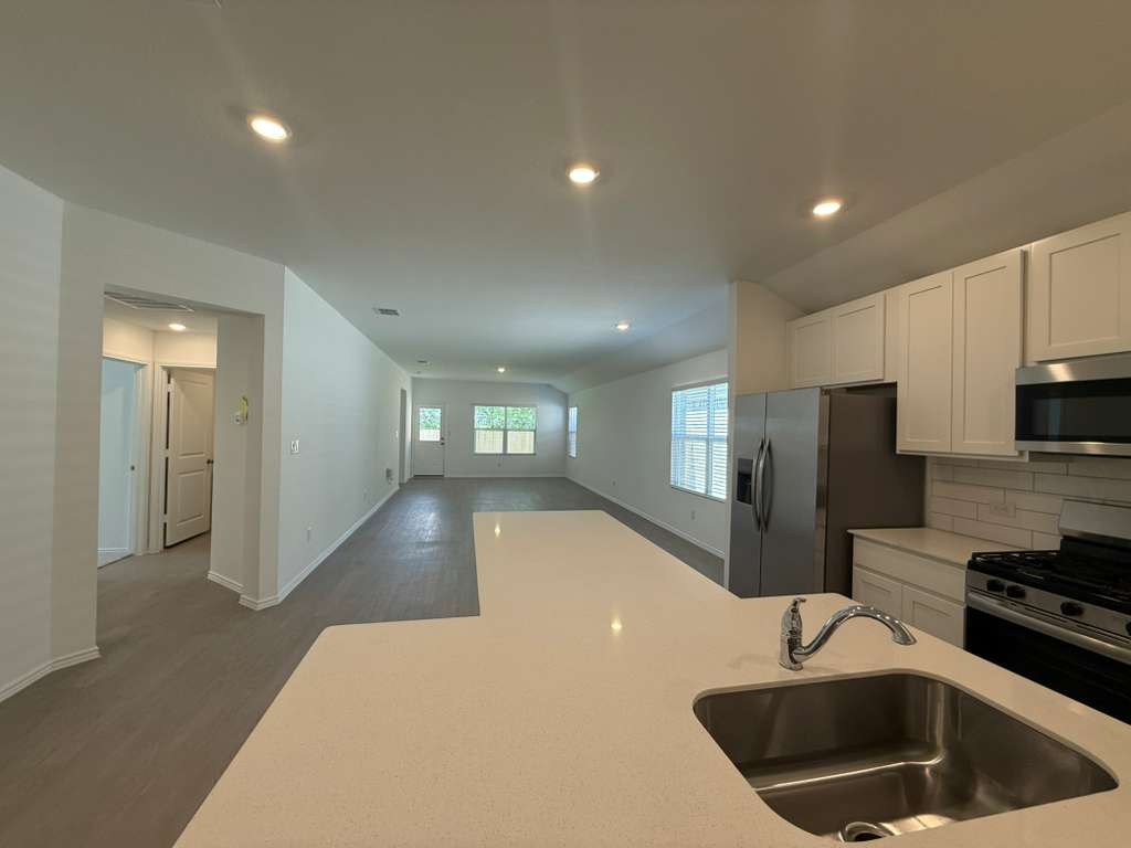 623 Sormonne Loop Kyle, TX 78640 - Photo 40 of 40 Kitchen featuring recessed lighting, stainless steel appliances, dark wood-style floors, white cabinetry, and open floor plan