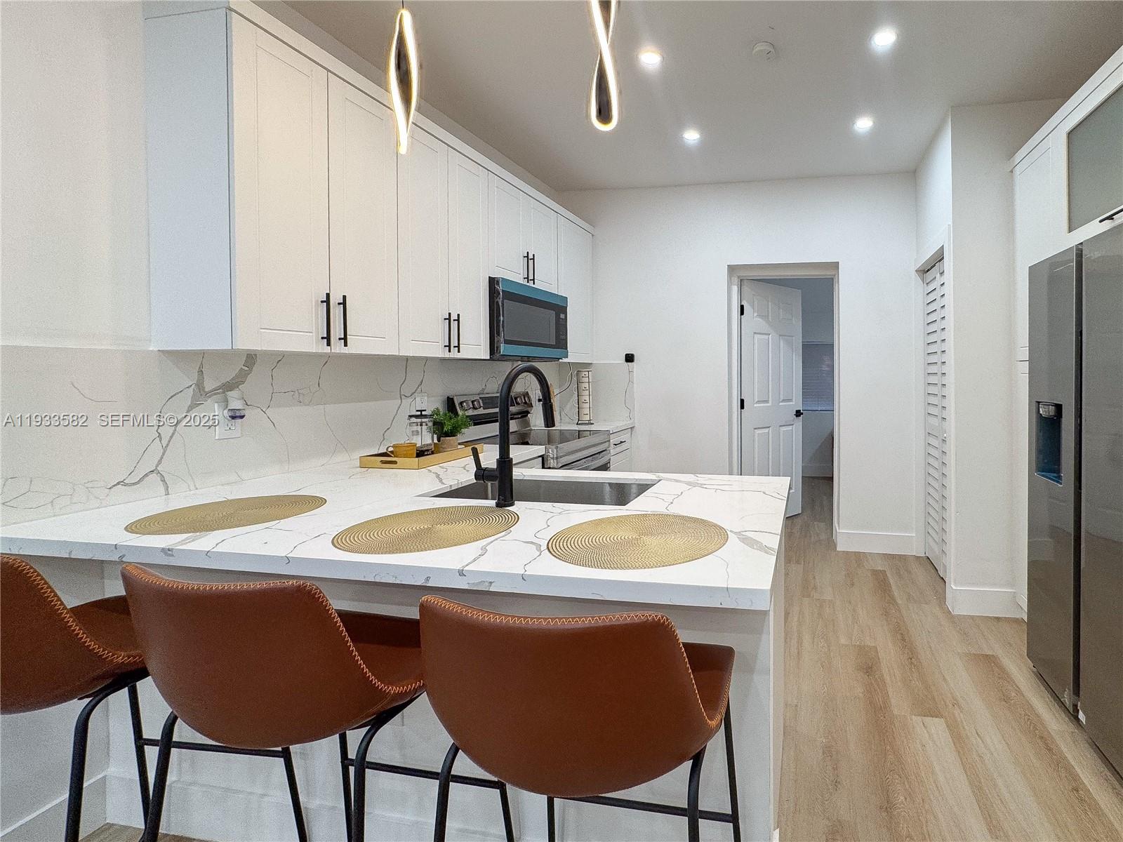 794 Northwest 44th Street Miami, FL 33127 - Photo 11 of 31 a kitchen with stainless steel appliances granite countertop a sink a microwave refrigerator and chairs