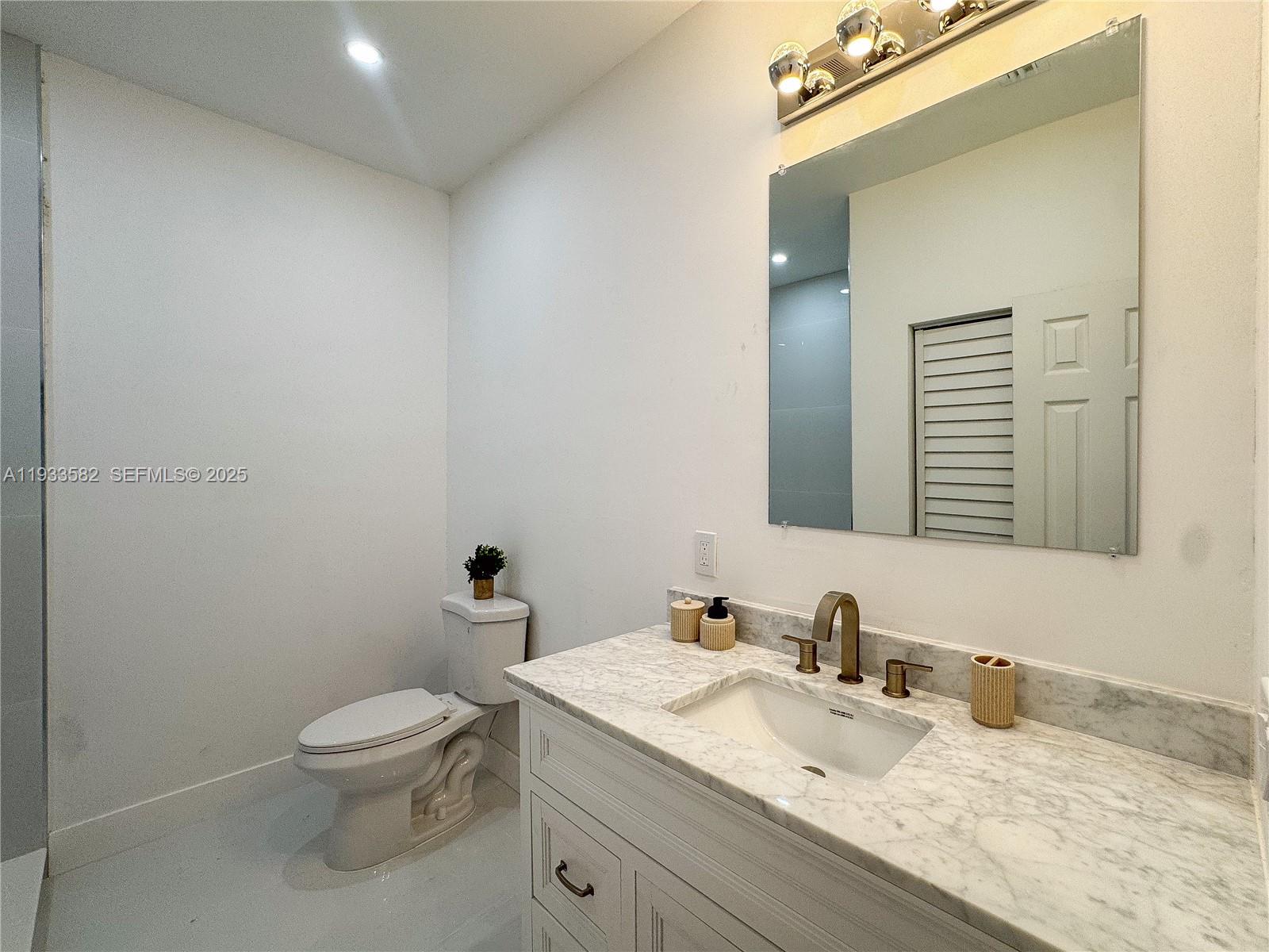794 Northwest 44th Street Miami, FL 33127 - Photo 16 of 31 a bathroom with a granite countertop sink mirror vanity and toilet