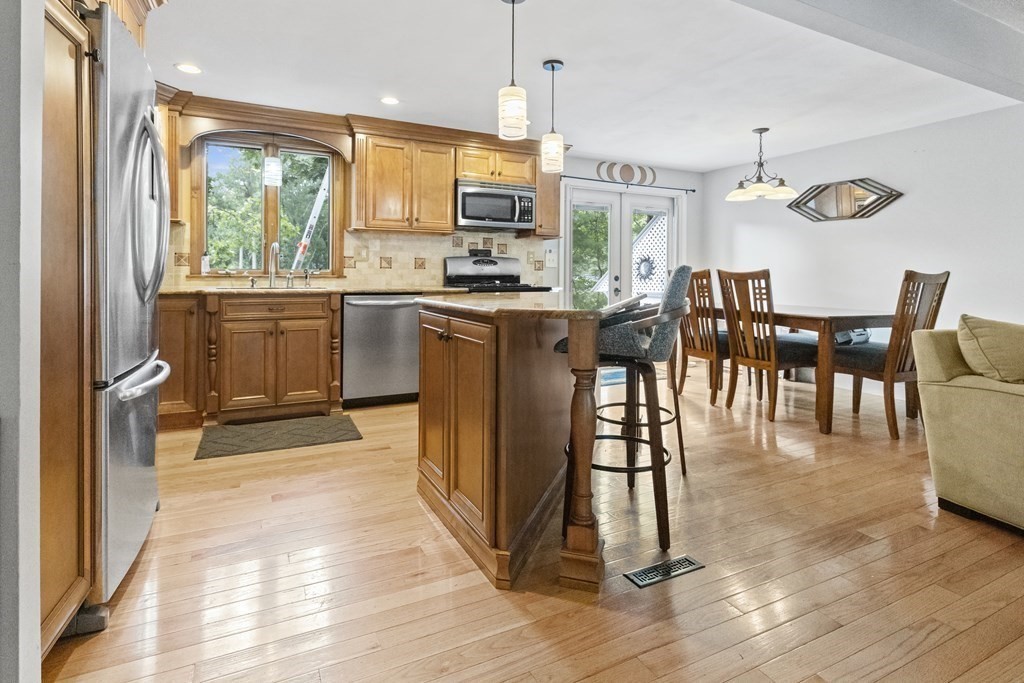 28 Edgewood Road Holbrook, MA 02343 - Photo 7 of 29 a kitchen with stainless steel appliances granite countertop a stove top oven a refrigerator a dining table and chairs with wooden floor