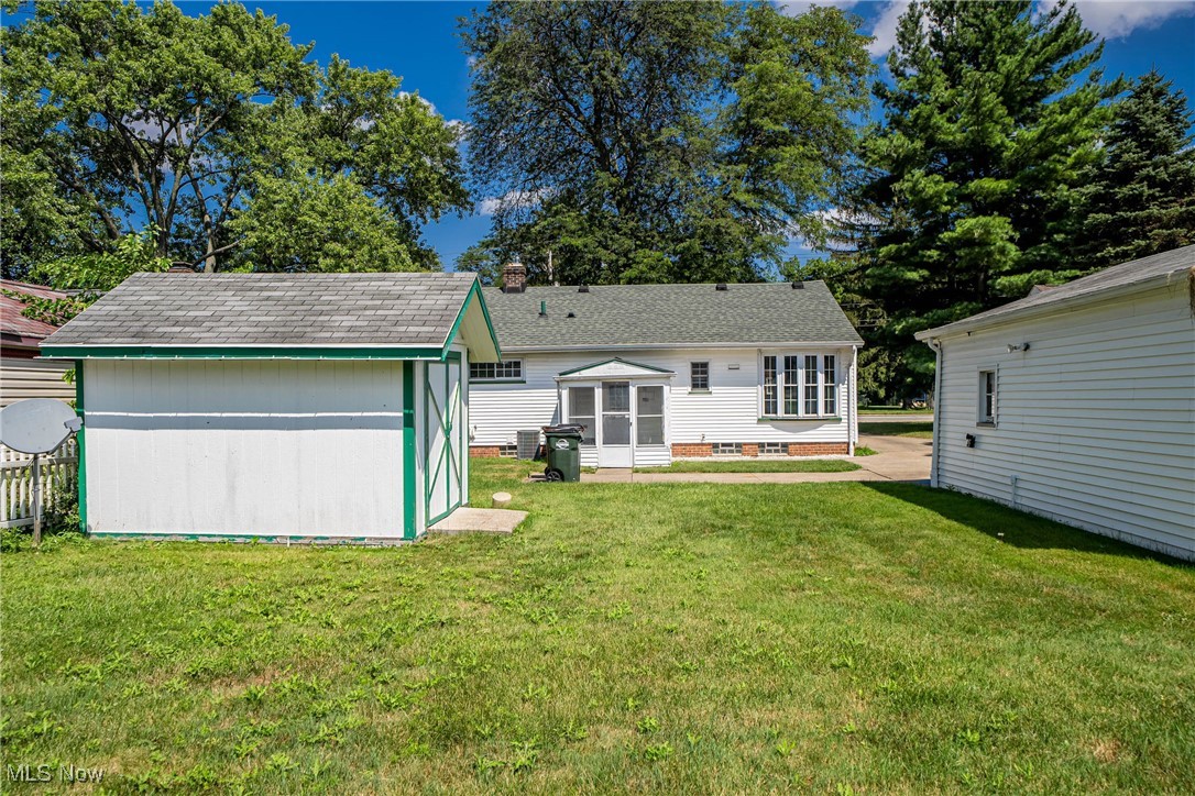 5526 Hauserman Road Cleveland, OH 44130 - Photo 21 of 26 Back of property with a lawn, a shed, a chimney, and roof with shingles