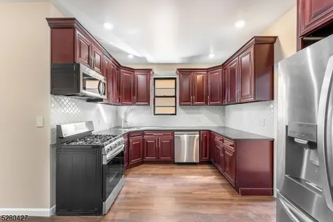 a kitchen with stainless steel appliances granite countertop wooden cabinets a stove top oven a sink and dishwasher