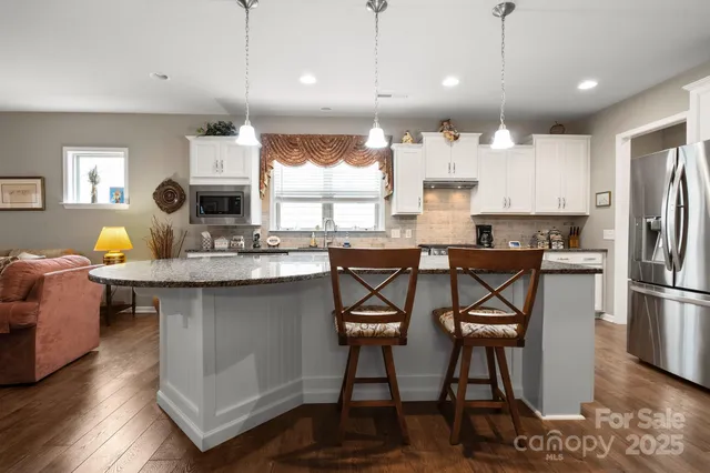 a kitchen with stainless steel appliances kitchen island granite countertop a table chairs sink and refrigerator