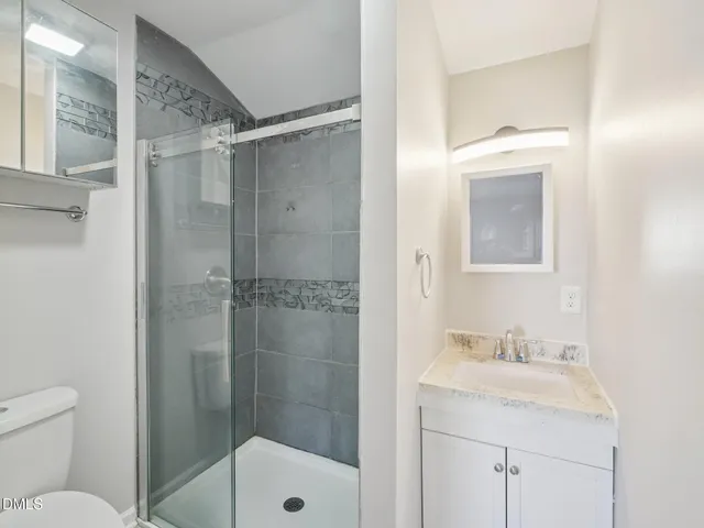 a bathroom with a shower sink vanity mirror and toilet