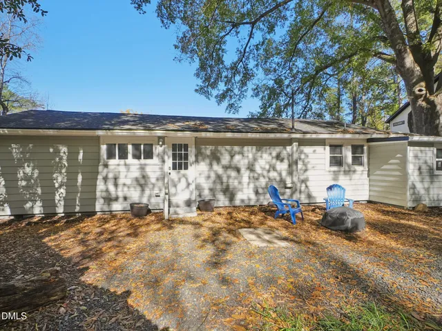 a backyard of a house with table and chairs and potted plants