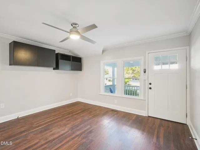 a view of an empty room with wooden floor and a window