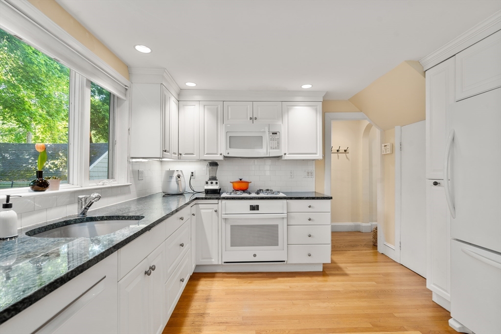 17 Charlotte Road Newton, MA 02459 - Photo 6 of 34 a kitchen with granite countertop white cabinets white appliances a sink and a large window