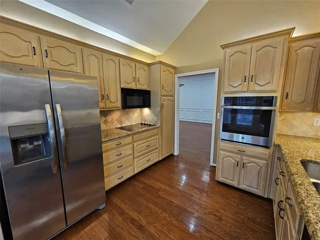 a kitchen with stainless steel appliances granite countertop a refrigerator a stove and a microwave