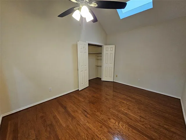 an empty room with wooden floor chandelier fan and windows