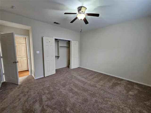 an empty room with chandelier fan and windows