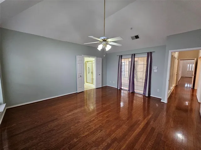 a view of an empty room with window and wooden floor