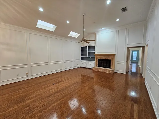 a view of empty room with wooden floor and fireplace