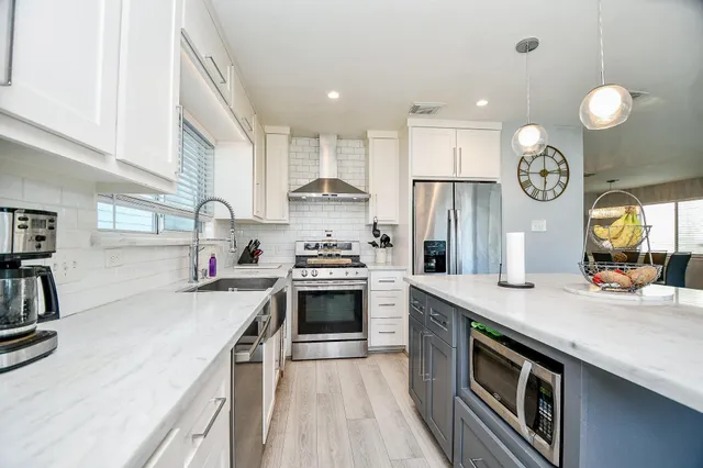 a kitchen with stainless steel appliances granite countertop a sink a stove and a refrigerator