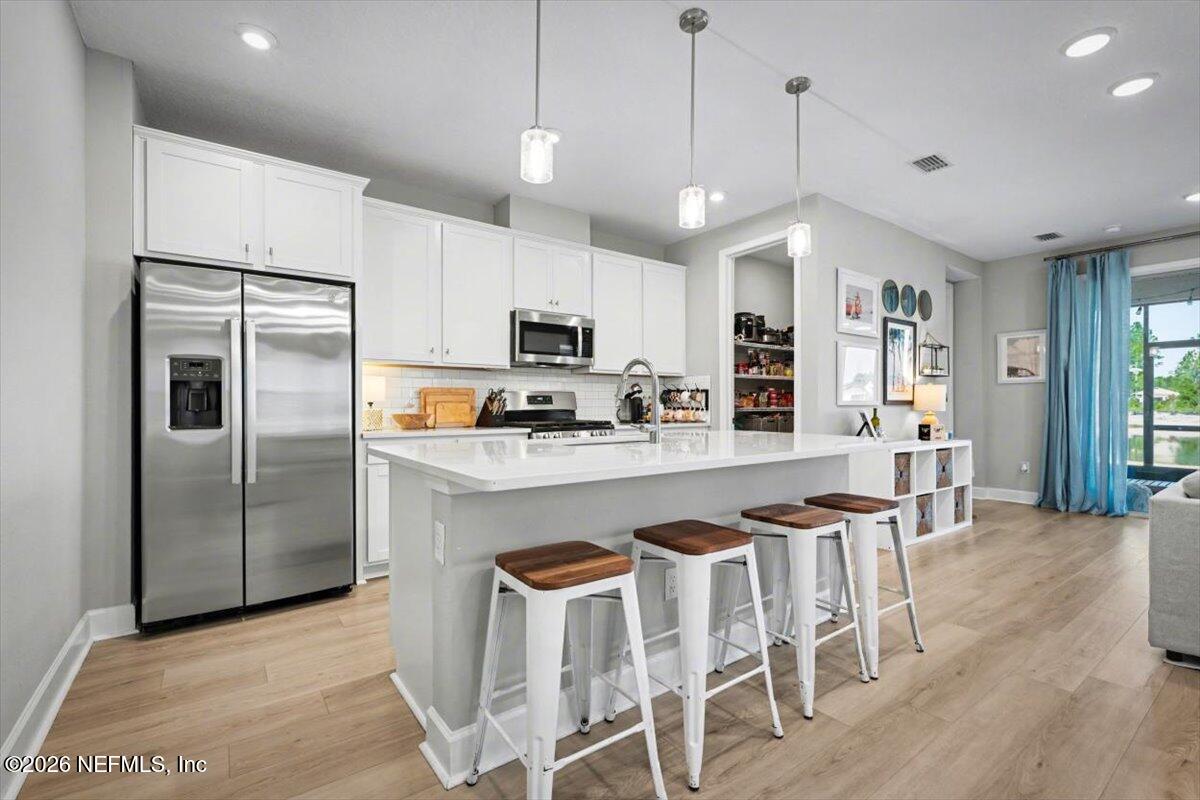 75315 Plumbago Yulee, FL 32097 - Photo 5 of 37 a kitchen with stainless steel appliances granite countertop a refrigerator a stove a microwave oven a sink a island and chairs with wooden floor