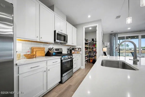 a kitchen with stainless steel appliances granite countertop a refrigerator a stove a microwave oven a sink a island and chairs with wooden floor