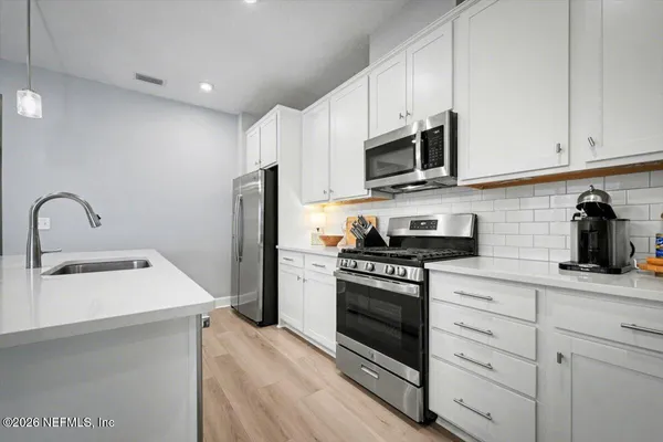a large kitchen with stainless steel appliances granite countertop a lot of counter space and wooden floor