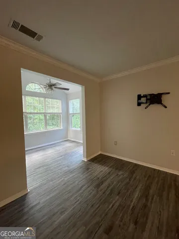 a view of an empty room with wooden floor and a window