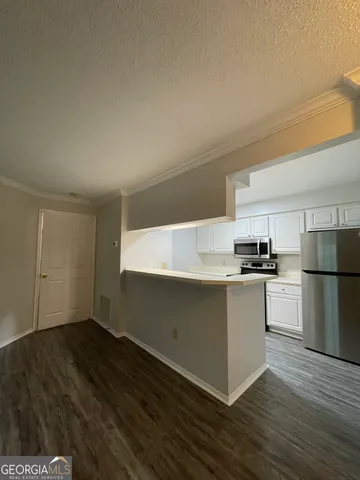 a kitchen with granite countertop a refrigerator and a stove top oven
