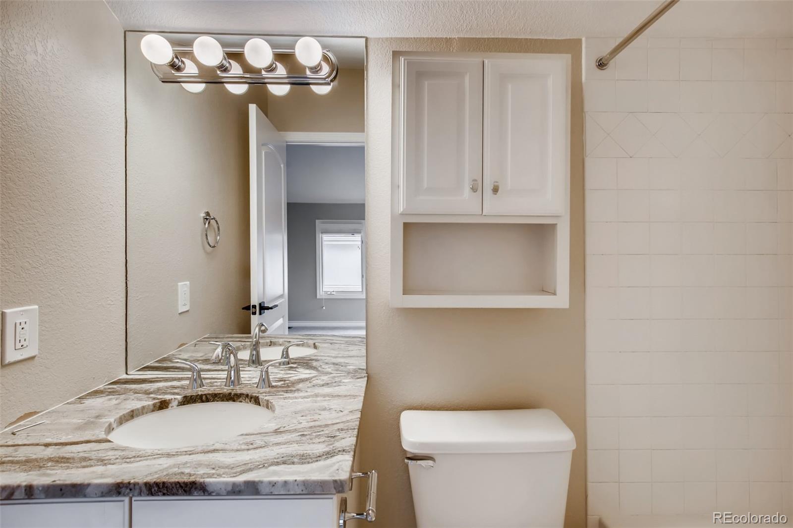 210 Cook Street Denver, CO 80206 - Photo 22 of 34 a bathroom with a granite countertop sink a toilet and a mirror