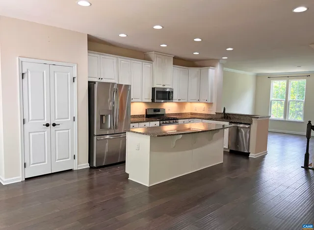 a kitchen with stainless steel appliances granite countertop a refrigerator a stove a sink and a microwave