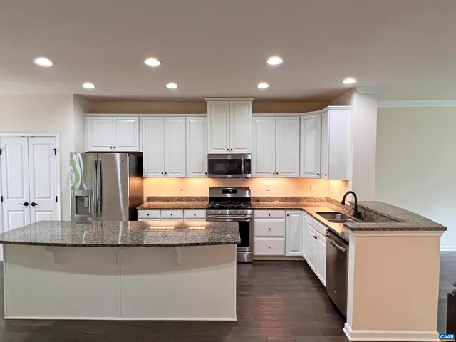 a kitchen with stainless steel appliances granite countertop a stove a sink and a refrigerator