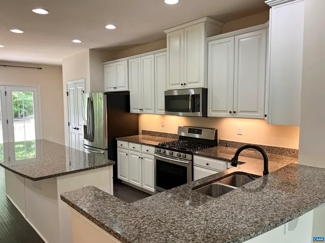 a kitchen with stainless steel appliances granite countertop a stove top oven a sink and a refrigerator
