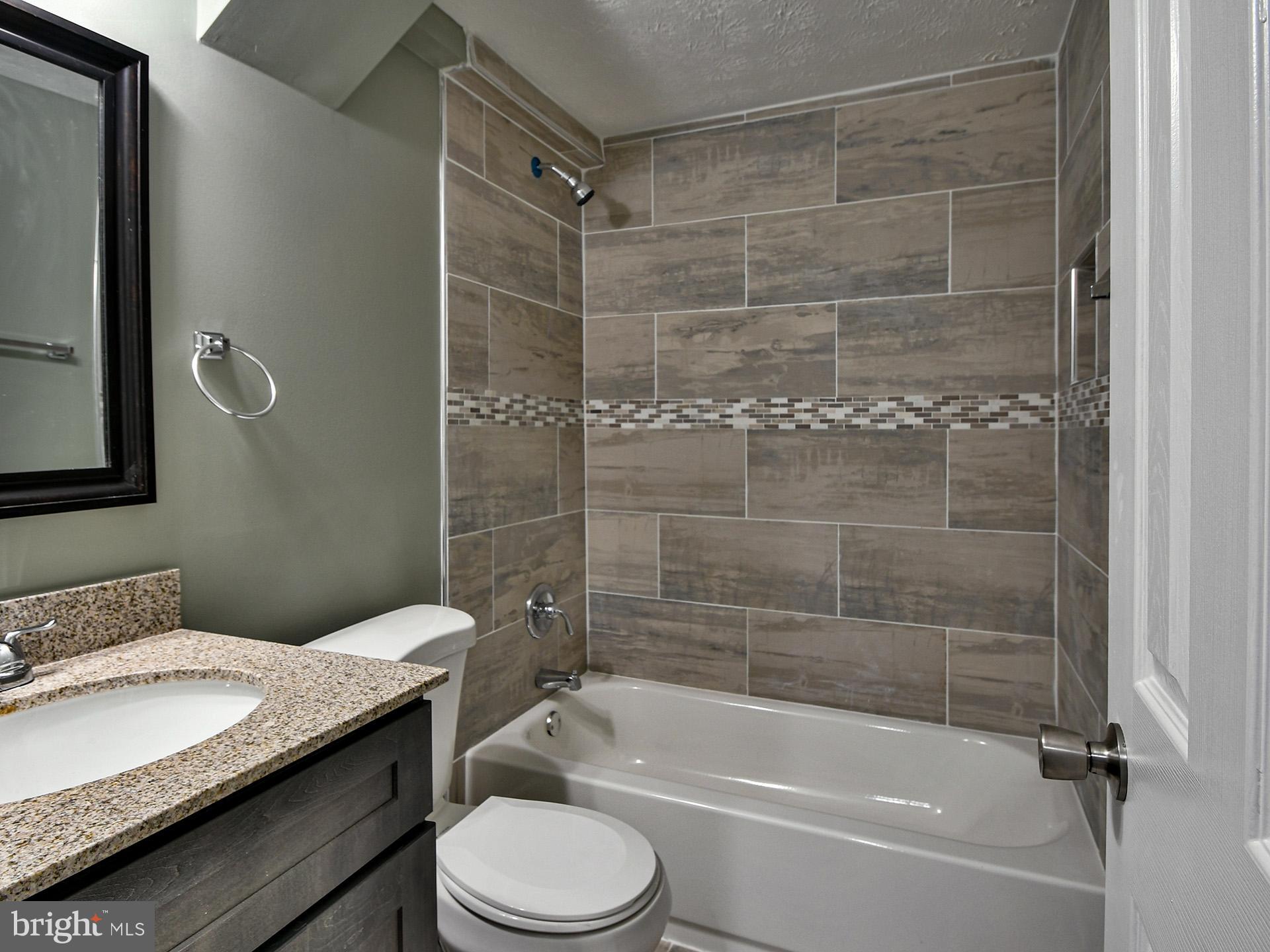3511 Castle Way, Unit 312 Silver Spring, MD 20904 - Photo 12 of 20 a bathroom with a granite countertop bathtub shower sink vanity and toilet