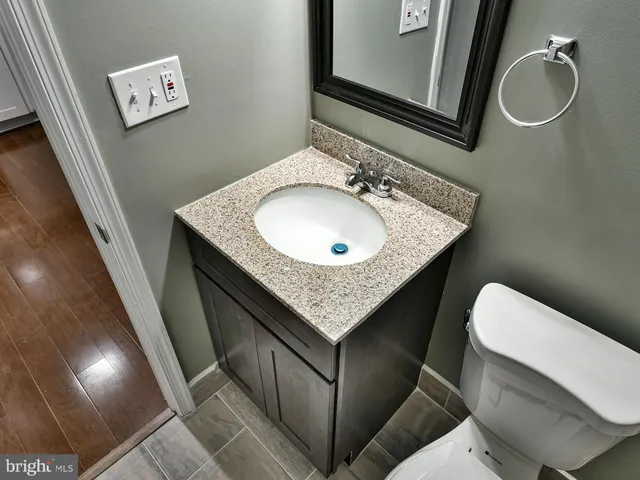 a bathroom with a granite countertop sink a toilet a mirror and vanity