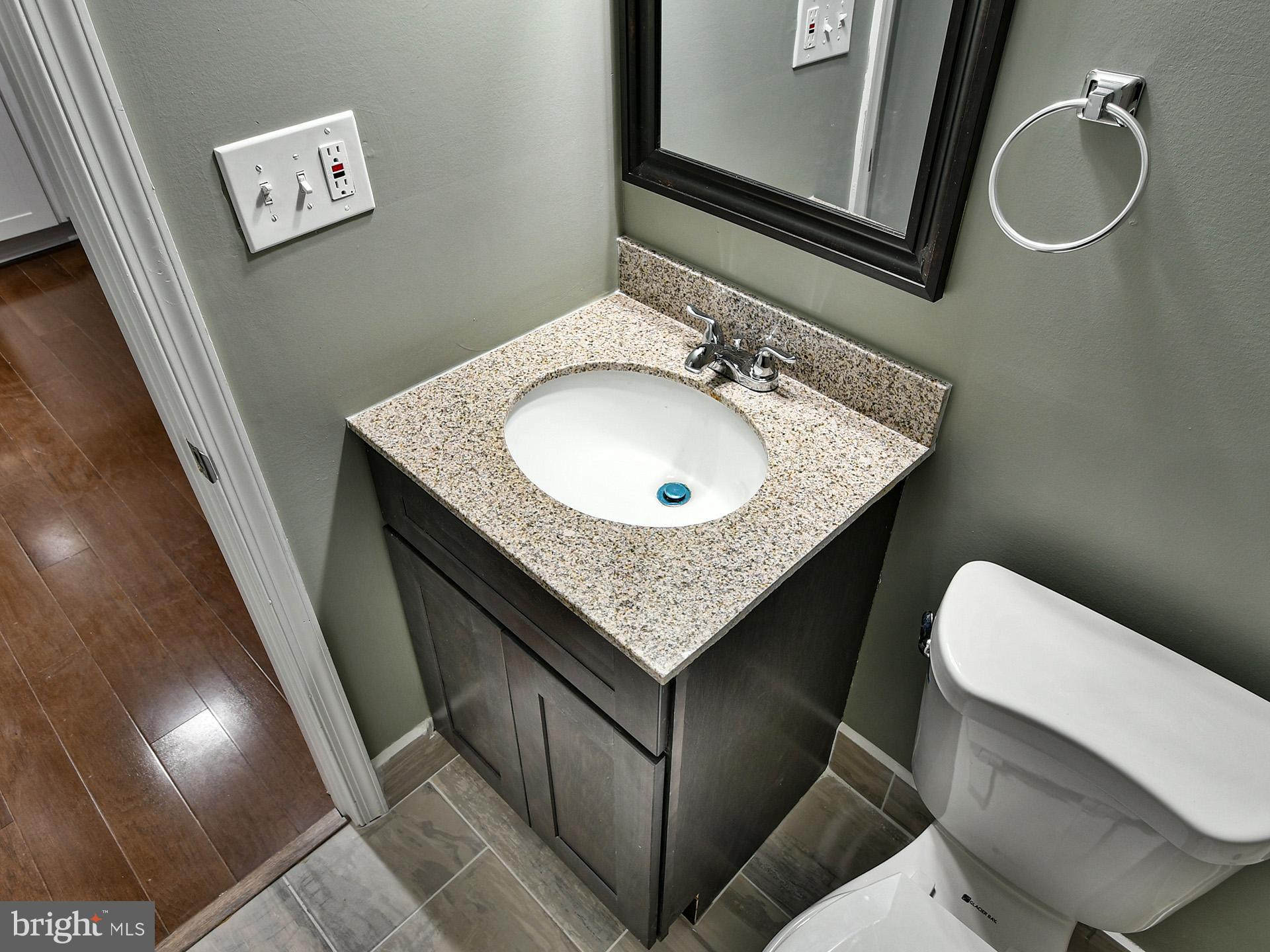 3511 Castle Way, Unit 312 Silver Spring, MD 20904 - Photo 13 of 20 a bathroom with a granite countertop sink a toilet a mirror and vanity