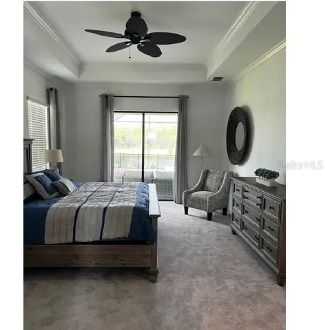 a spacious bedroom with a bed a chandelier and a large window