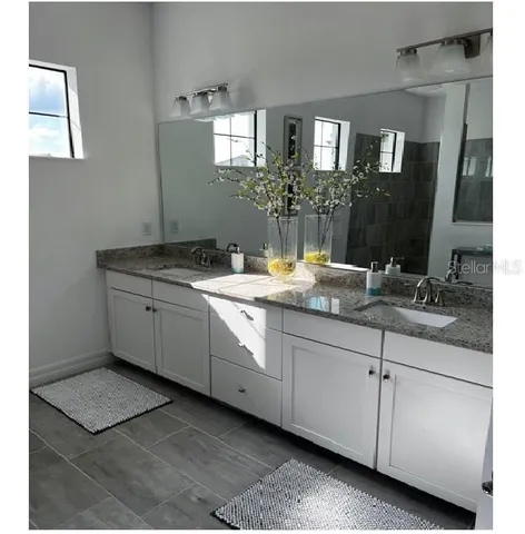 a bathroom with a granite countertop sink two mirror and a
