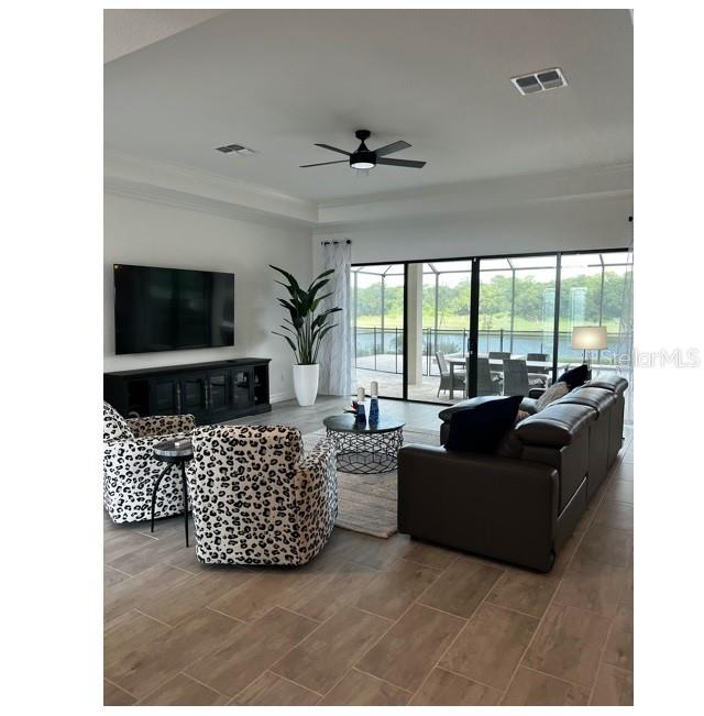 17021 Polo Trail Lakewood Ranch, FL 34211 - Photo 8 of 42 a living room with furniture a flat screen tv and a floor to ceiling window