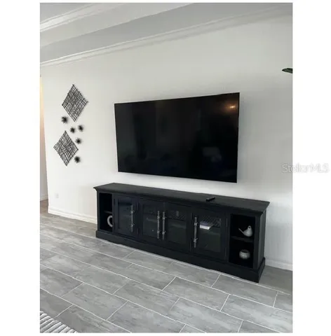 a living room with stainless steel appliances kitchen island granite countertop a fireplace and a flat screen tv